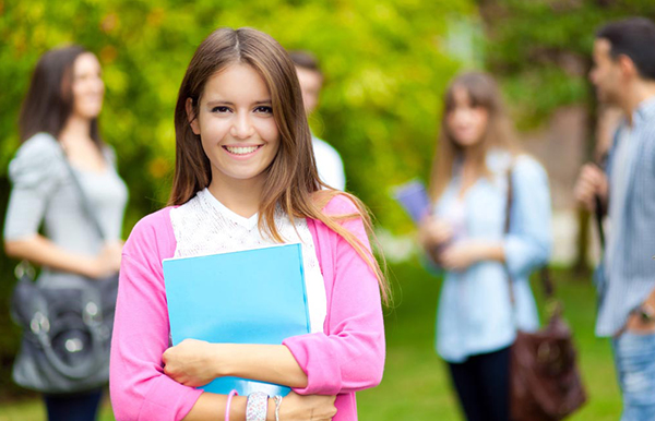 College student smiling while holding a folder in hand
